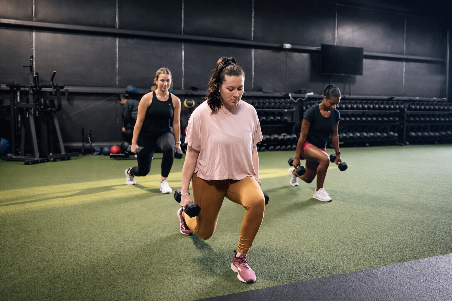 A group fitness class performing weighted lunges